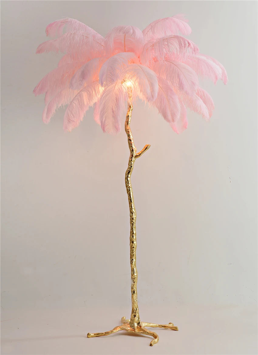 Palm tree lamp with pink leaves and gold base on a plain background