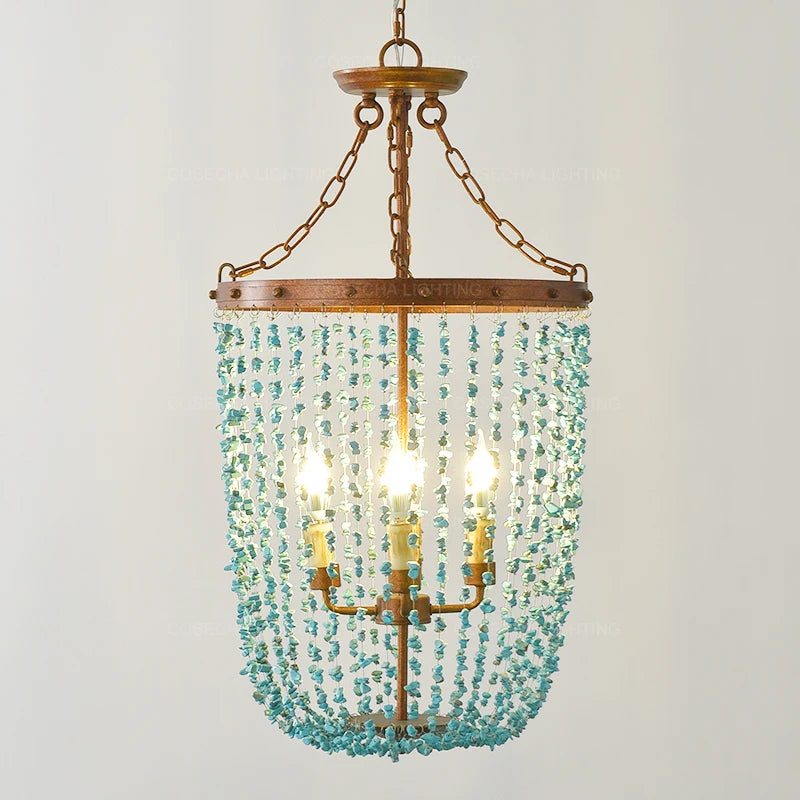 Turquoise stone beads cascading from a distressed gold frame on a multi-light chandelier, front view.