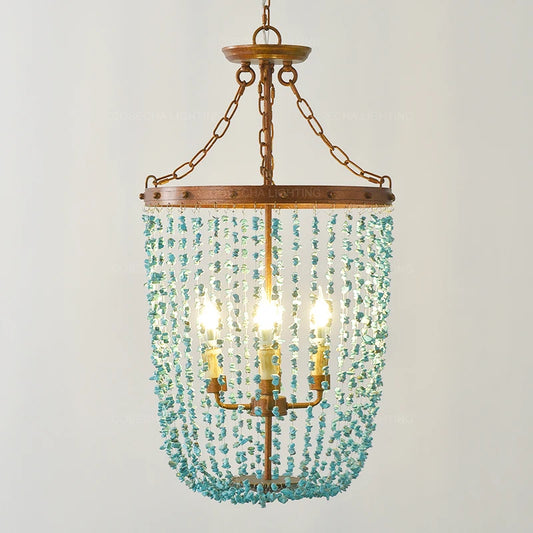 Turquoise stone beads cascading from a distressed gold frame on a multi-light chandelier, front view.