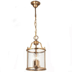Close-up of a small brass cylinder glass chain pendant light against a white background
