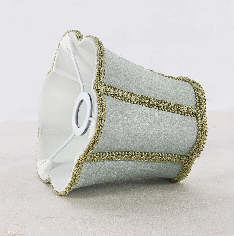 Underside view of a sky blue fabric lampshade showing its white interior and the metal frame for attachment.