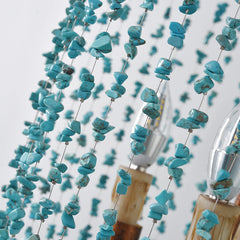 Close-up view of turquoise stone beads strung on wires, with LED bulbs visible in the background of the chandelier.