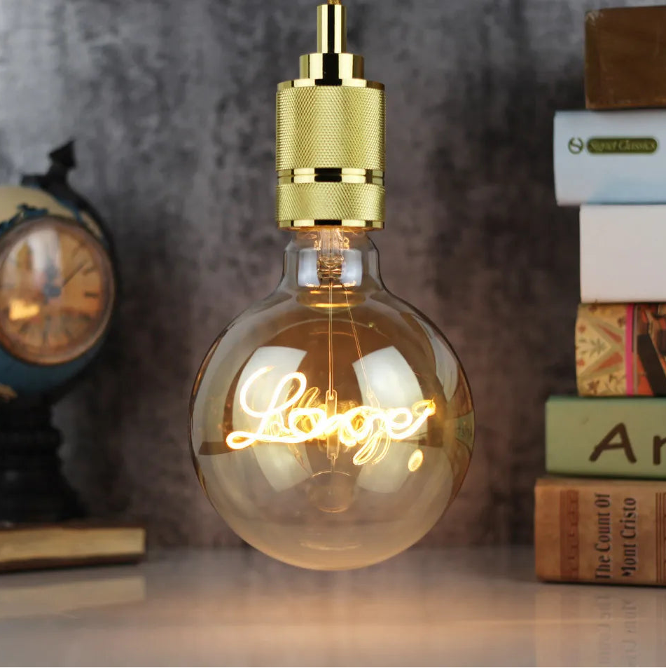 Decorative light bulb with 'Hello' text on a shelf with books and a clock.