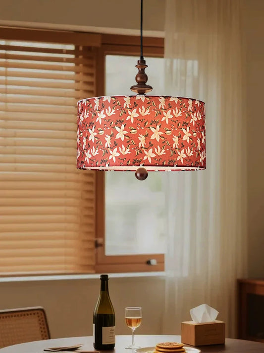 Red floral fabric drum pendant light with wood accents above a dining table