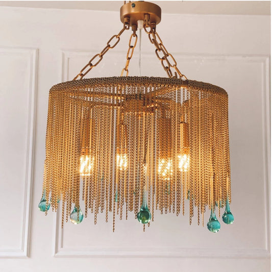 Gold chain tassel teardrop pendant light hanging from a ceiling against a white paneled wall