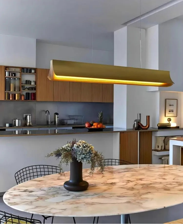 Modern kitchen with a gold pendant light, marble table, and decorative elements.