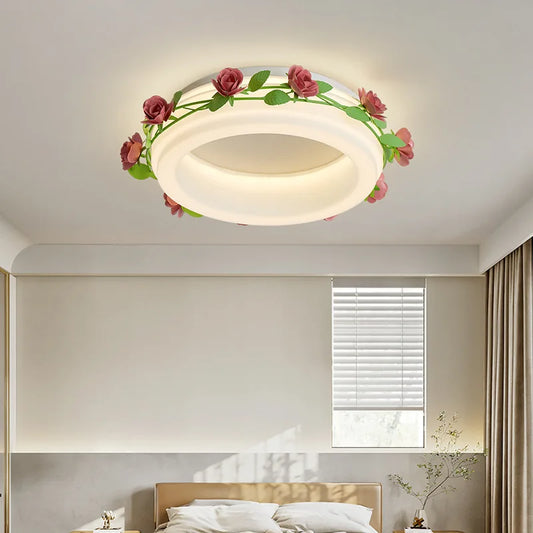 A bedroom interior featuring a white semi-flush ceiling light with a floral rose vine design, illuminated above a bed.