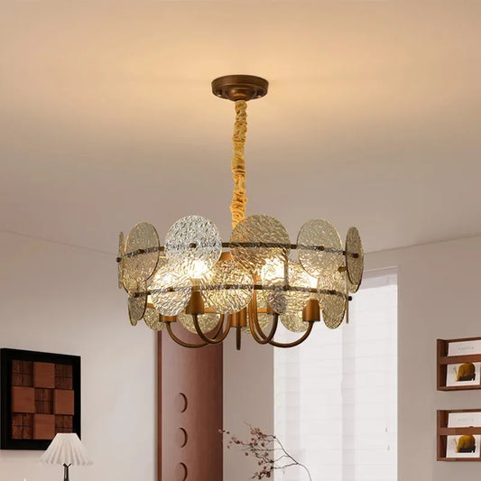 Close-up of a brushed gold chandelier with circular frosted glass elements arranged around the frame, illuminated from within.
