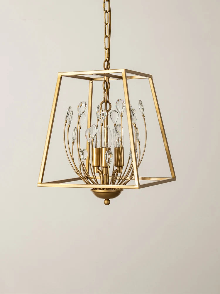 A detail shot of a gold metal cage pendant light, focusing on the arrangement of clear teardrop crystals and the central light bulbs.