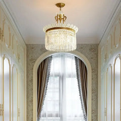 A gold and crystal tiered chandelier with cascading teardrop crystals, shown hanging in a hallway with arched doorways and built-in cabinets.