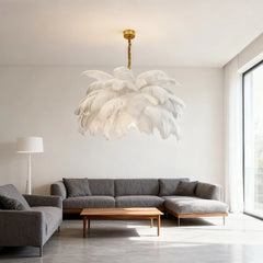 White feather chandelier with gold accents in a bright, minimalist living room with a grey sofa.