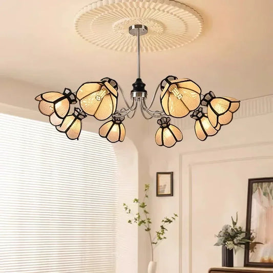 A close-up view of a polished chrome chandelier with light beige, petal-shaped shades accented with black trim.