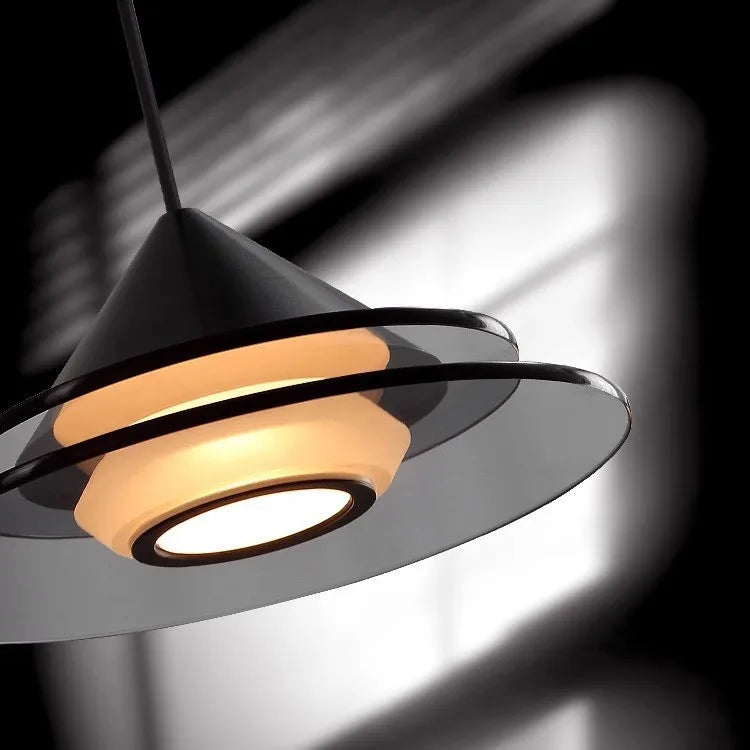 A black tiered pendant light illuminates a bedside area with a soft glow.