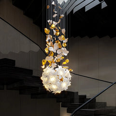 Close-up of a gold and white floral chandelier with crystal accents, showcasing its intricate design and warm lighting.
