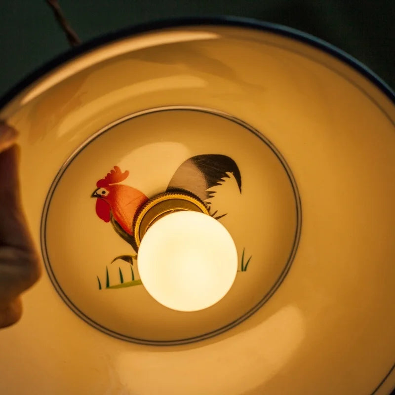 Decorative light fixture with a rooster design on a dark background