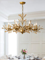 A brushed gold crystal chandelier with floral details installed over a dining table setting.