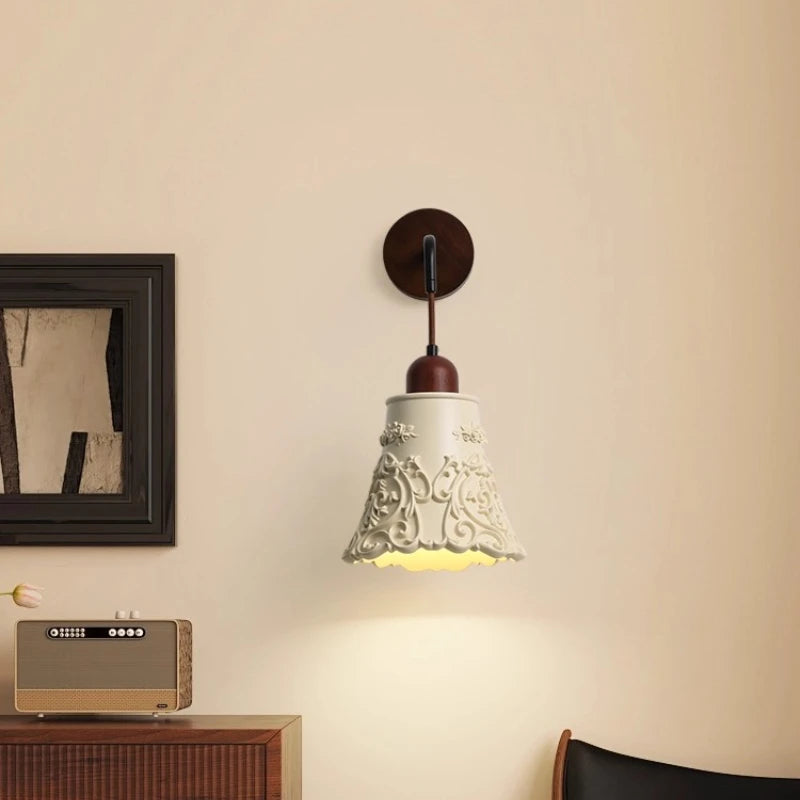Decorative wall lamp on a beige wall with a framed picture and radio in the background.