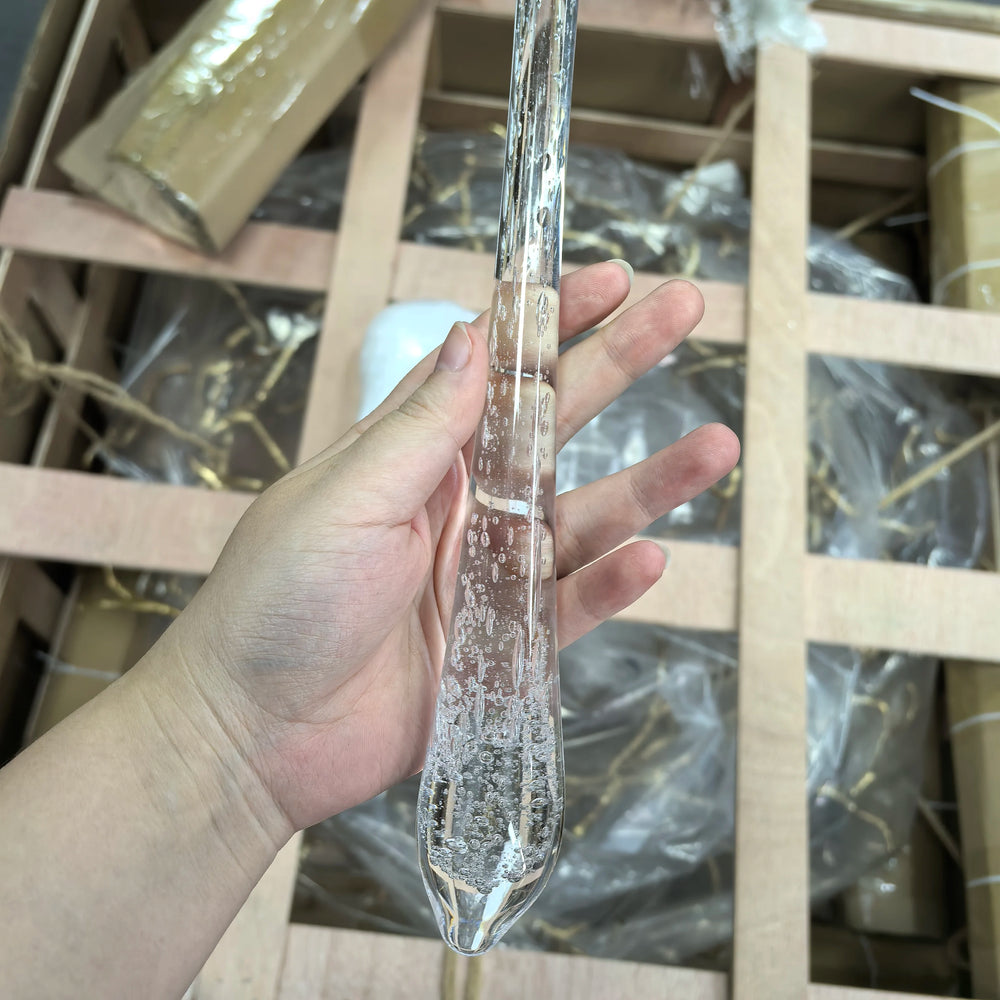 Clear glass object held by a hand with a wooden and plastic background