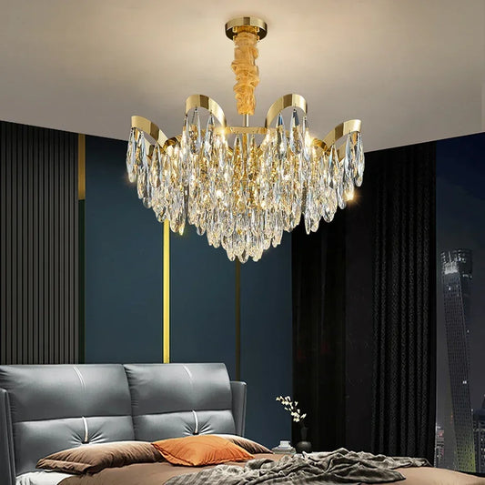Gold cascading chandelier with teardrop crystals hanging above a bed