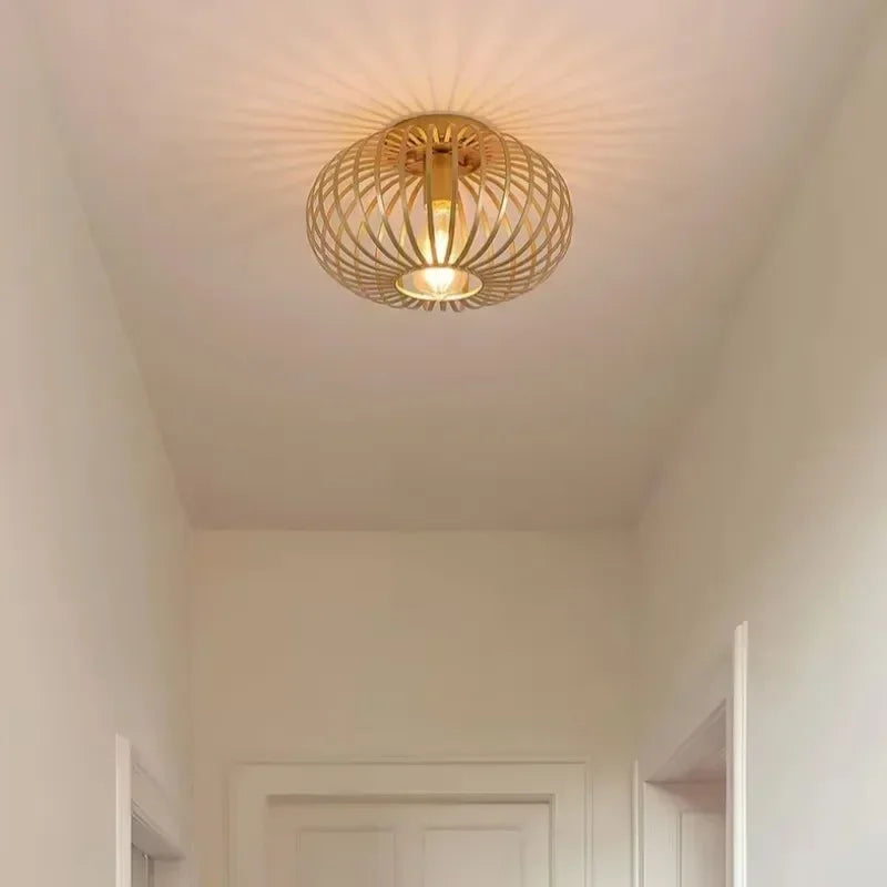 Gold open cage semi-flush ceiling light casting light patterns on the ceiling.