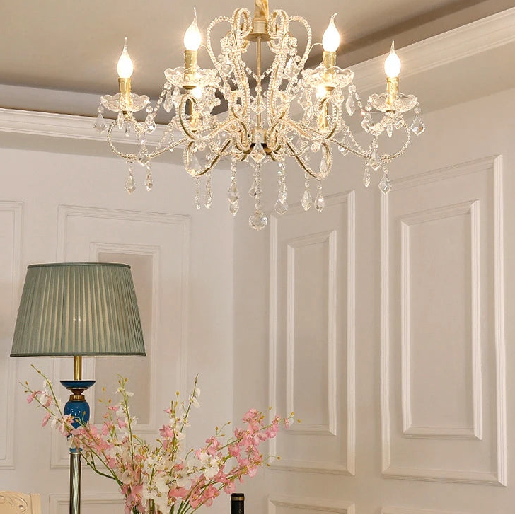 Crystal chandelier in a room with floral arrangement and lamp.