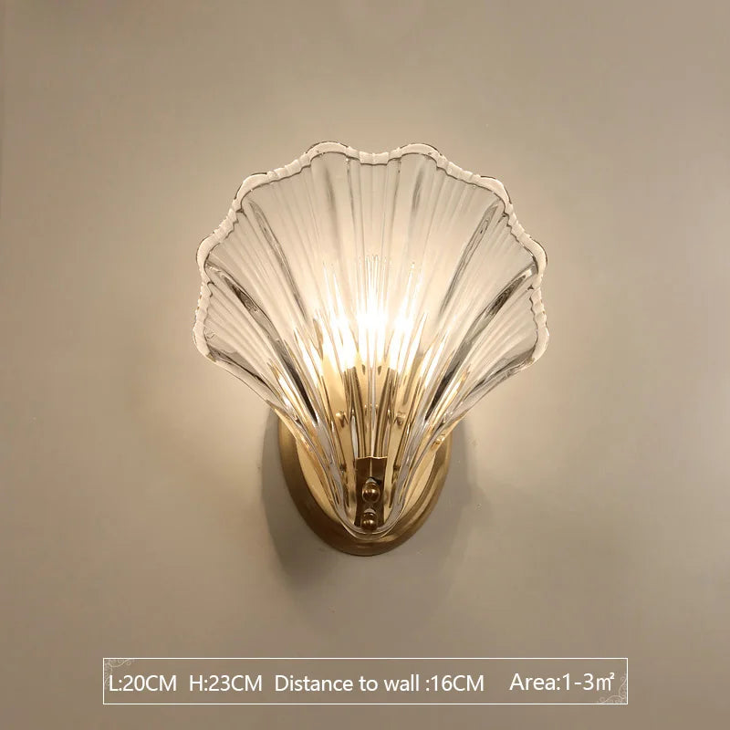 Wall-mounted light fixture with shell-shaped glass shade on a beige wall.