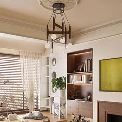 A living room with beige walls and blinds, showcasing a dark wood and glass multi-arm chandelier above a bookshelf.