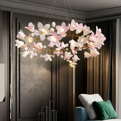 Side view of a pink and white floral chandelier with a copper finish, suspended above a contemporary sofa.