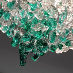 Detail shot of the clear and green glass-like crystals suspended from a circular chrome fixture.