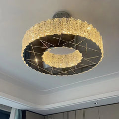 Modern spiral crystal flush mount chandelier with faceted crystals and a dark metallic center, illuminated against a white ceiling.