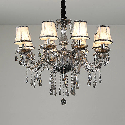 A close-up view of a smoke gray crystal chandelier with fabric shades and cascading crystal droplets against a white ceiling.