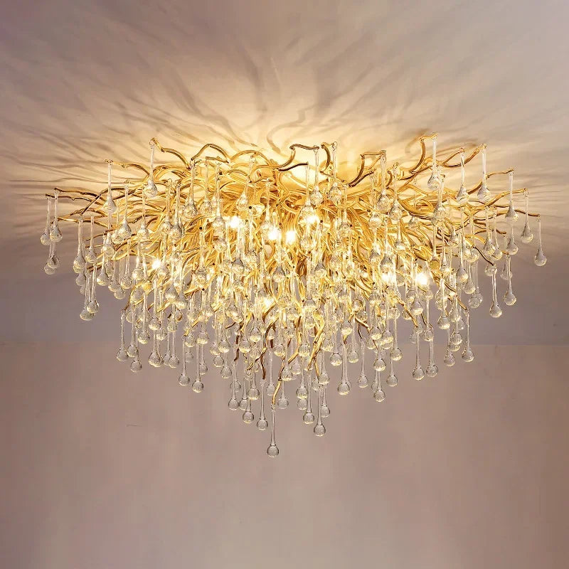 A wide shot showing the gold crystal chandelier illuminating a dining area with a marble table and yellow flowers.
