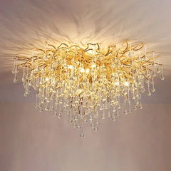 A wide shot showing the gold crystal chandelier illuminating a dining area with a marble table and yellow flowers.