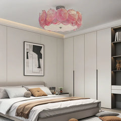 Pink glass floral flush mount ceiling light in a modern bedroom with minimalist decor.