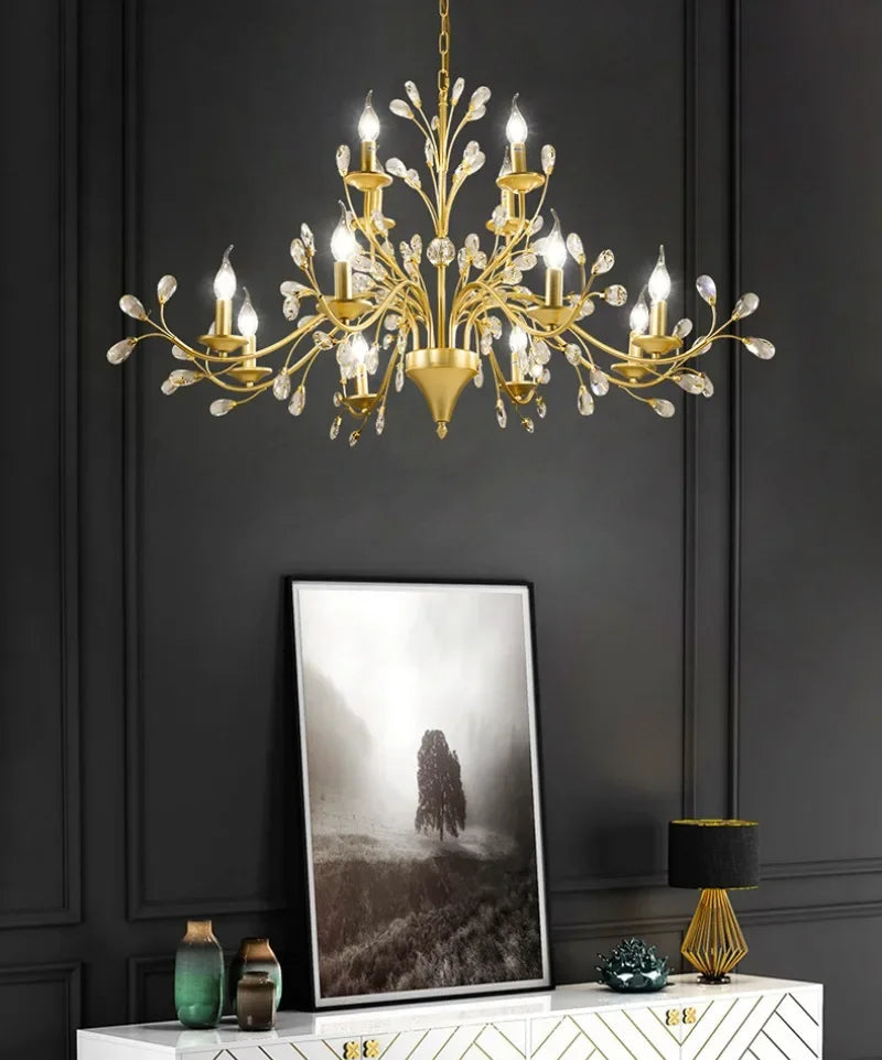 Gold chandelier hanging above a white console table with decorative items against a dark wall.