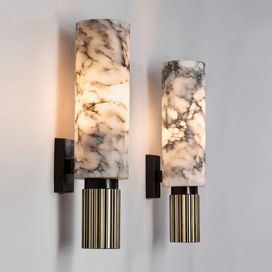 Two wall sconces featuring natural marble shades and reeded brass bases against a white background.