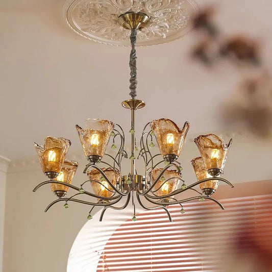 A close-up view of a bronze chandelier with amber glass shades and floral accents, mounted on a white ceiling.