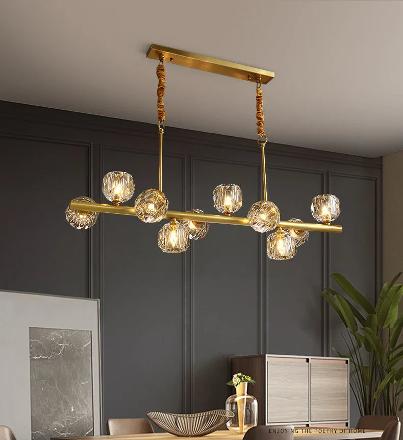 Modern gold chandelier with glass shades in a room with dark walls and a table.