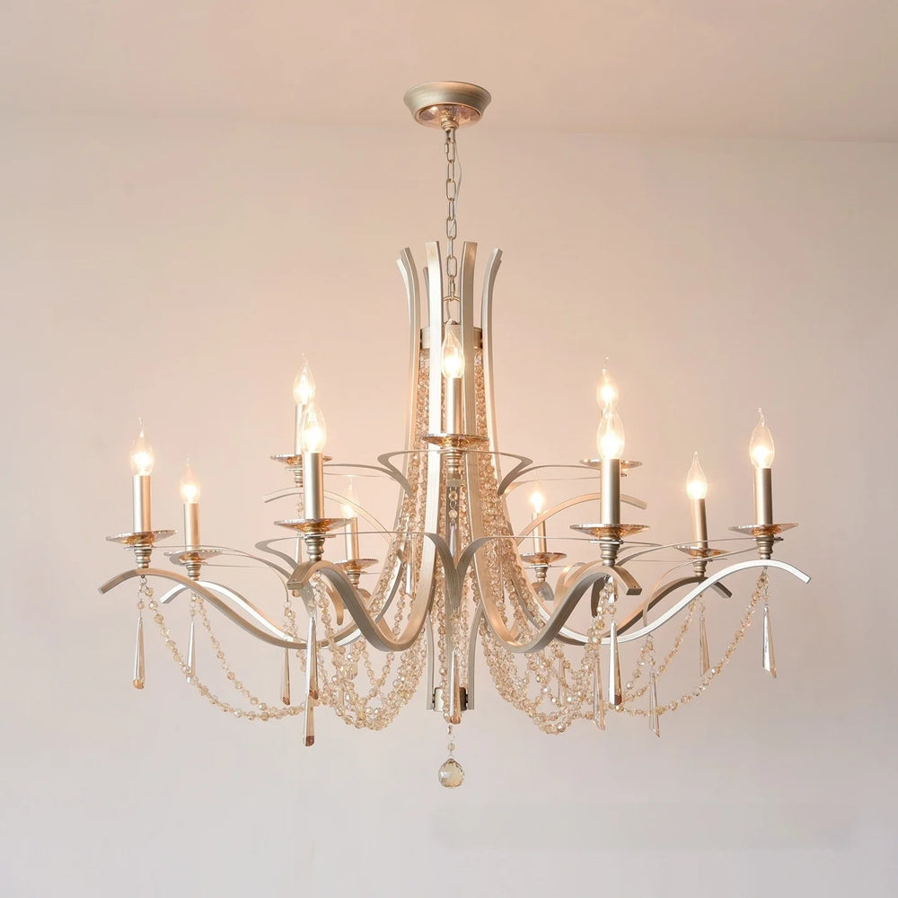 Brushed gold tiered chandelier with cascading crystal drops and candle-style LED bulbs, mounted on a white ceiling.