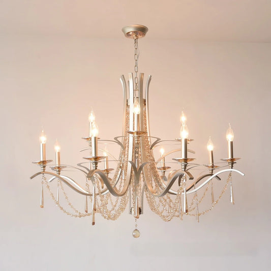 Brushed gold tiered chandelier with cascading crystal drops and candle-style LED bulbs, mounted on a white ceiling.