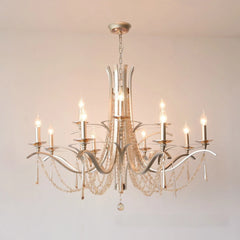 Brushed gold tiered chandelier with cascading crystal drops and candle-style LED bulbs, mounted on a white ceiling.