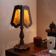 A table lamp with a textured glass shade and a dark wooden stand is displayed on a wooden surface.