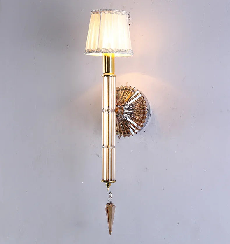 Decorative wall sconce with gold finish and crystal accents on a light gray background
