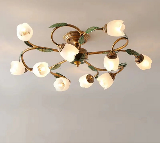 A close-up view of a gold multi-arm ceiling light with white tulip-shaped glass shades and green leaf accents, against a plain background.