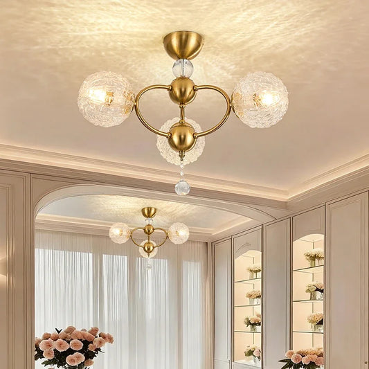 Gold semi-flush ceiling light with textured glass globe shades and crystal accents, mounted on a white ceiling.