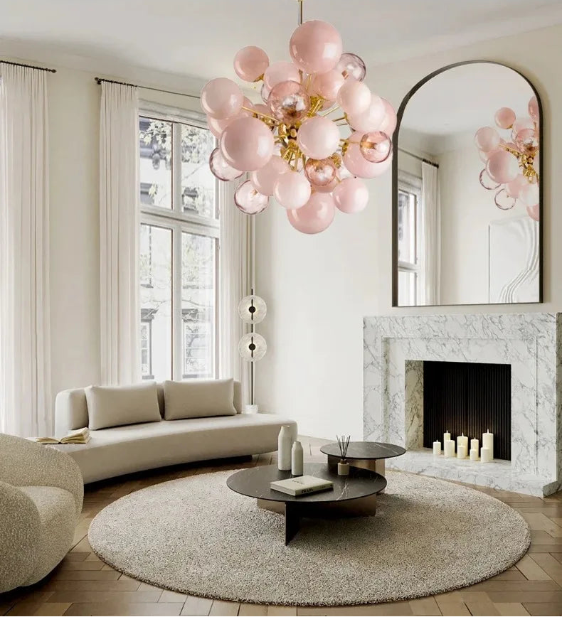 Modern living room with pink balloon chandelier, white sofa, and marble fireplace.
