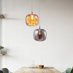 Two crystal ball pendant lights, one amber and one smoke gray, hanging over a wooden dining table.