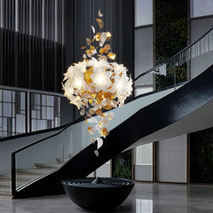 A dramatic chandelier with gold floral elements and crystal accents cascading down along a modern spiral staircase.