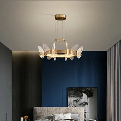 A gold butterfly ring pendant light with clear crystal accents installed in a bedroom.