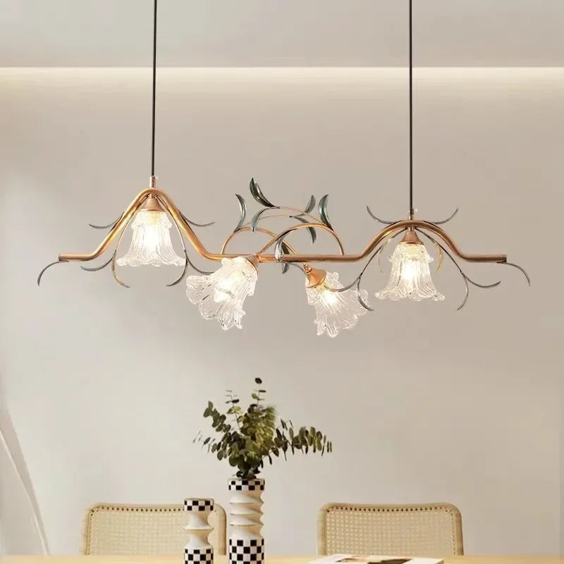 A gold floral branch pendant light with four glass shades suspended in a dimmer setting.